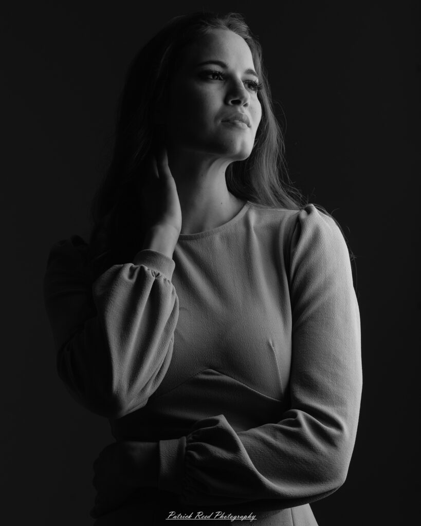 A studio portrait a confident female model in an elegant blue dress, photographed with dramatic studio lighting on August 23, 2025.