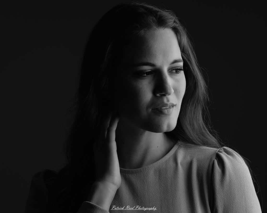 A studio portrait a confident female model in an elegant blue dress, photographed with dramatic studio lighting on August 23, 2025.