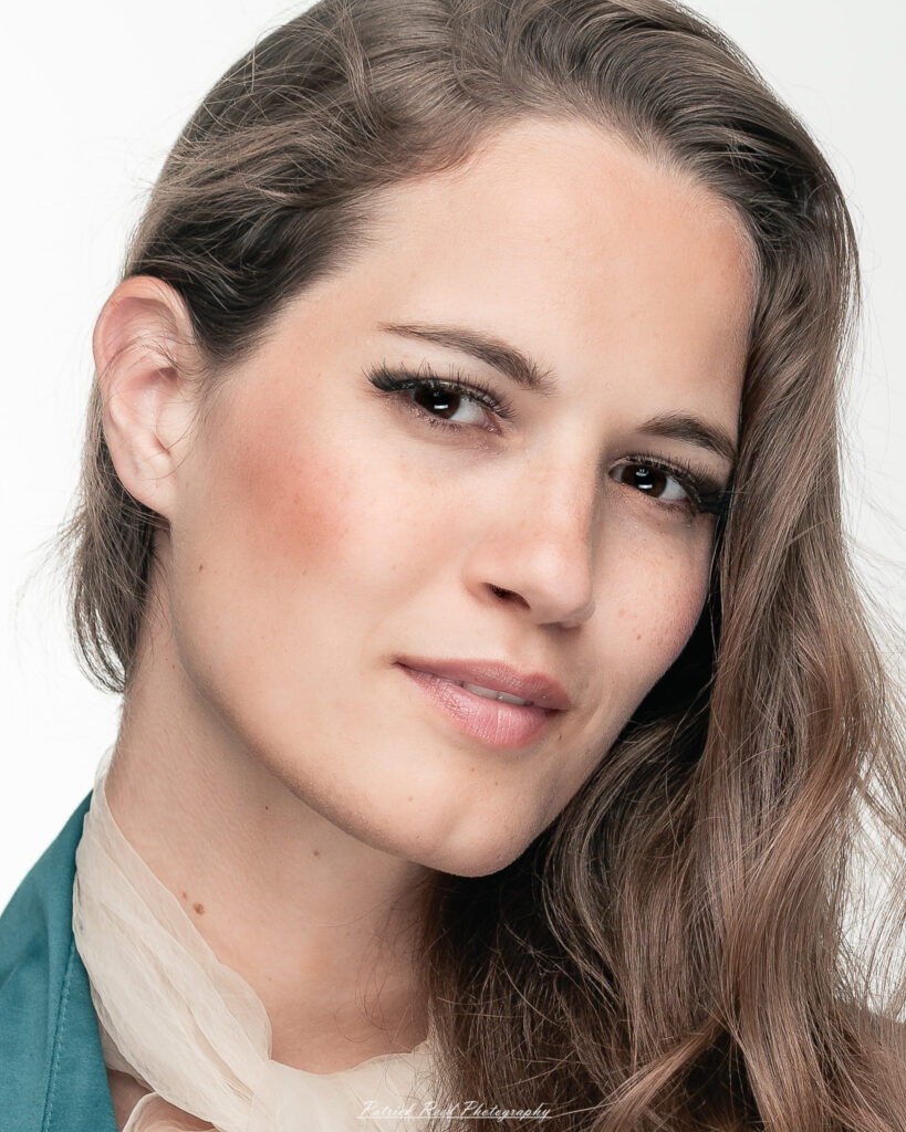 A studio portrait a confident female model in an elegant blue dress, photographed with dramatic studio lighting on August 23, 2025.