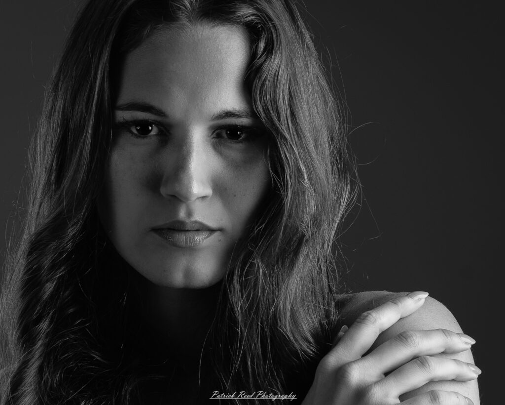 A studio portrait a poised female model in a sleek black dress, photographed under controlled lighting on August 23, 2025.