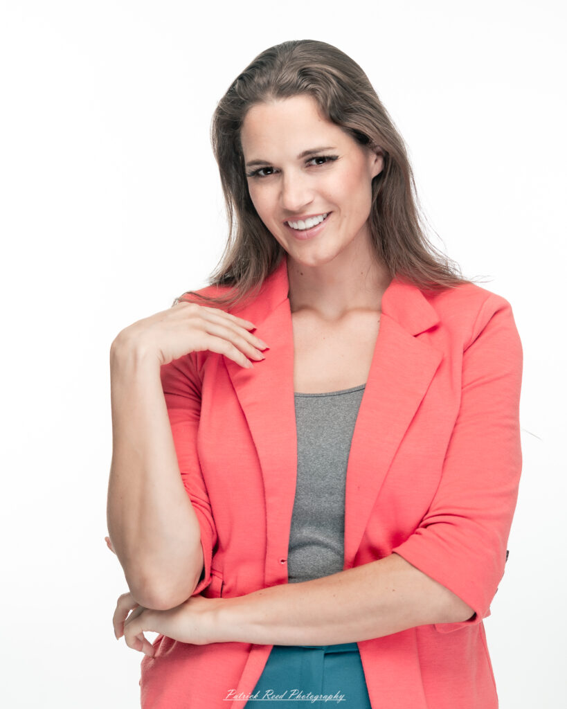 A dramatic studio portrait of a woman in a pink shirt, photographed on August 23, 2025, with bold lighting that emphasizes contrast and texture.