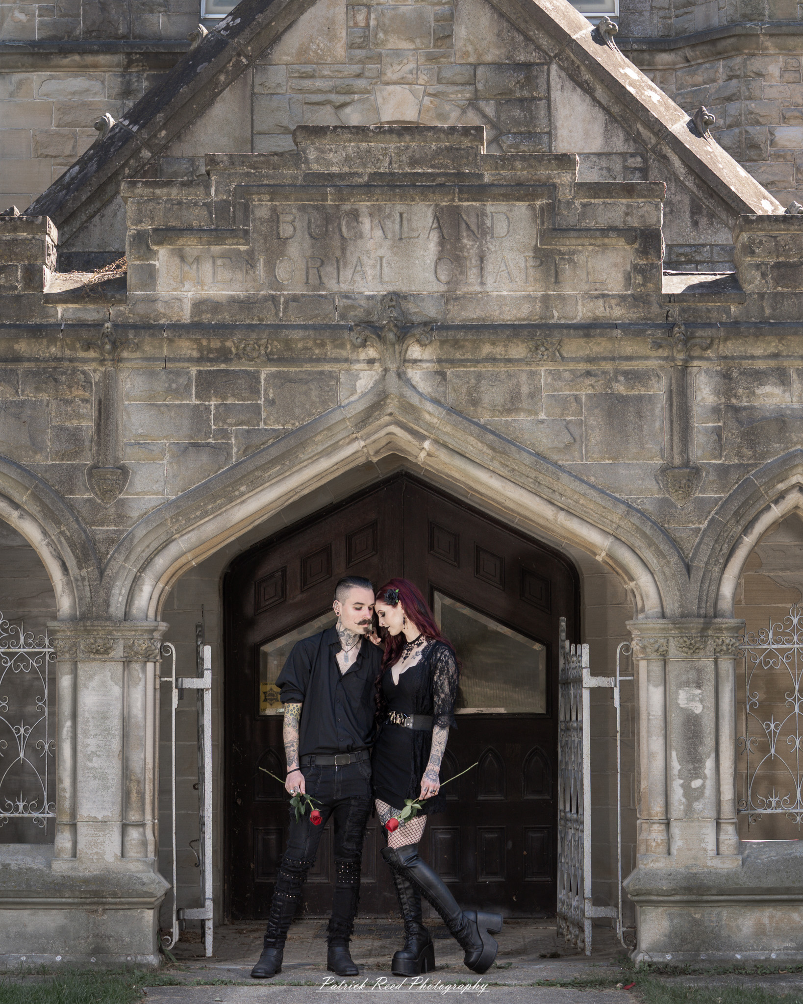 A gothic-themed portrait of a model named Minerva with a partner, photographed in a cemetery on September 28, 2025, featuring dark attire, moody lighting, and dramatic composition.