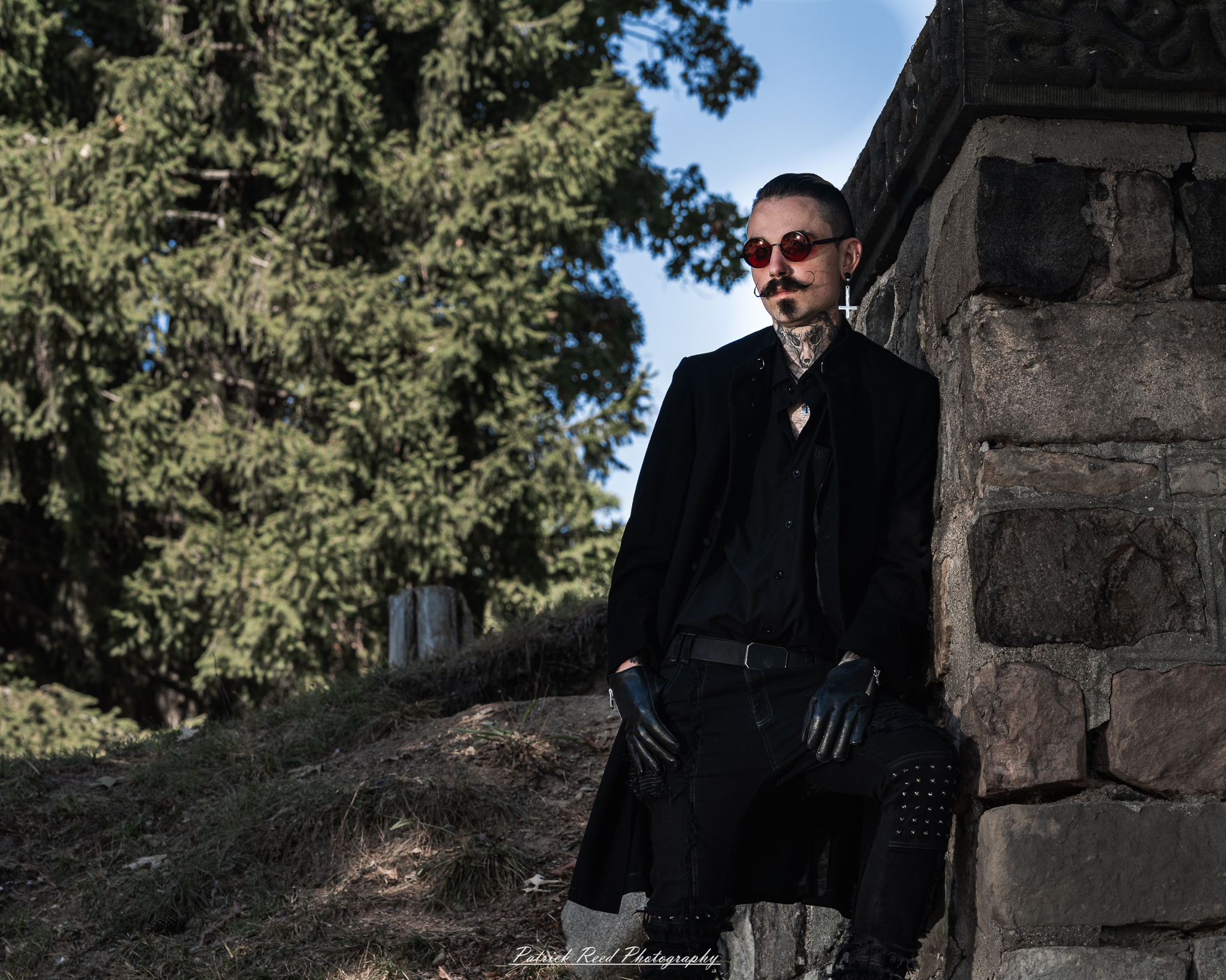 A gothic-themed portrait of a model named Minerva with a partner, photographed in a cemetery on September 28, 2025, featuring dark attire, moody lighting, and dramatic composition.