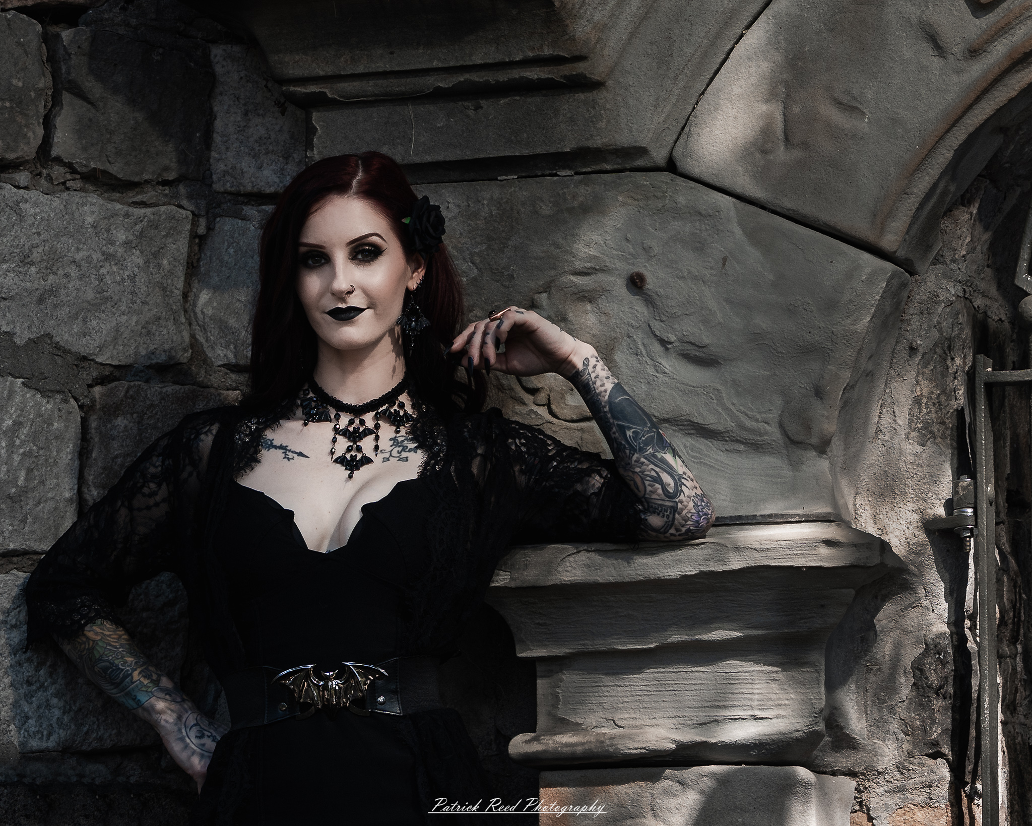 A gothic-themed portrait of a model named Minerva with a partner, photographed in a cemetery on September 28, 2025, featuring dark attire, moody lighting, and dramatic composition.