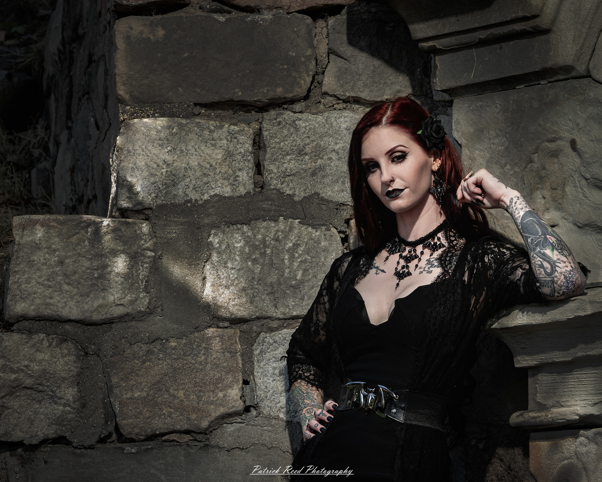 A gothic-themed portrait of a model named Minerva with a partner, photographed in a cemetery on September 28, 2025, featuring dark attire, moody lighting, and dramatic composition.