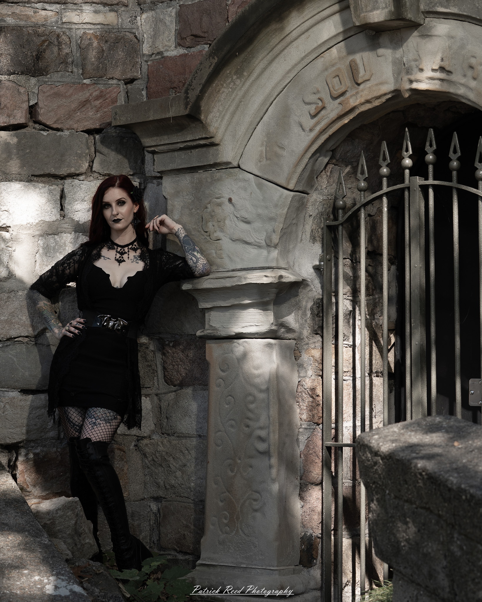A gothic-themed portrait of a model named Minerva with a partner, photographed in a cemetery on September 28, 2025, featuring dark attire, moody lighting, and dramatic composition.