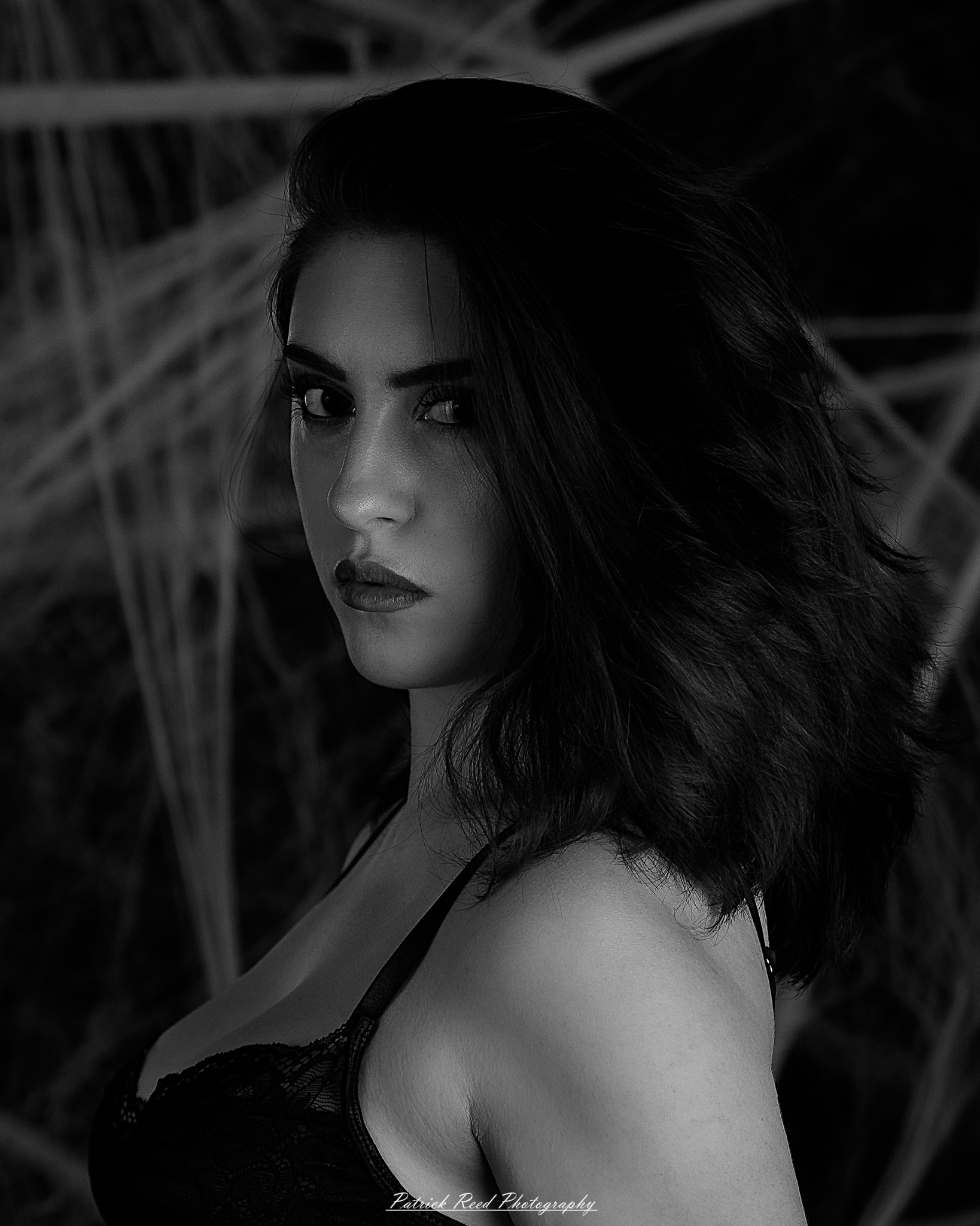 A portrait of a woman named Jinx surrounded by artificial spiderwebs, photographed on October 29, 2025. The lighting is dramatic and moody, emphasizing the texture of the webs and her expression.