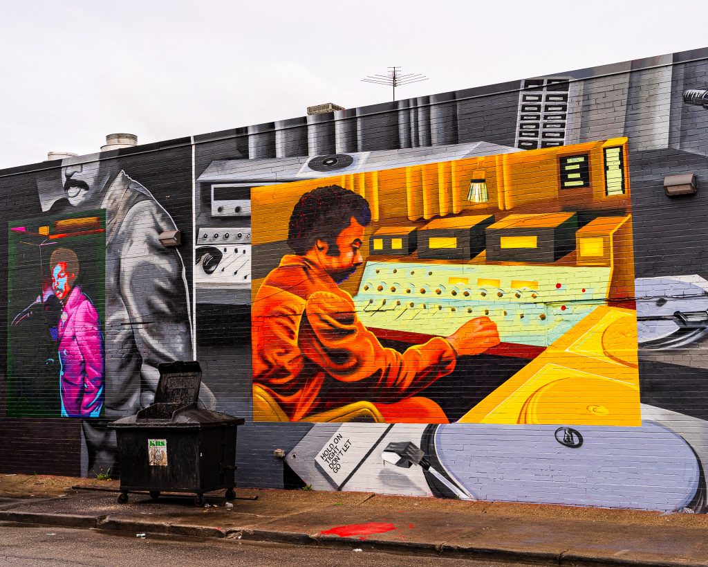 Large-scale mural in Eastern Market Detroit with layered graffiti textures and urban street art composition.
