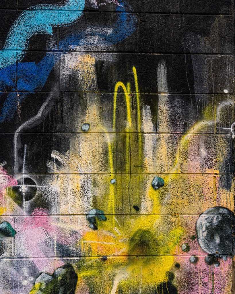 Large-scale mural in Eastern Market Detroit with layered graffiti textures and urban street art composition.