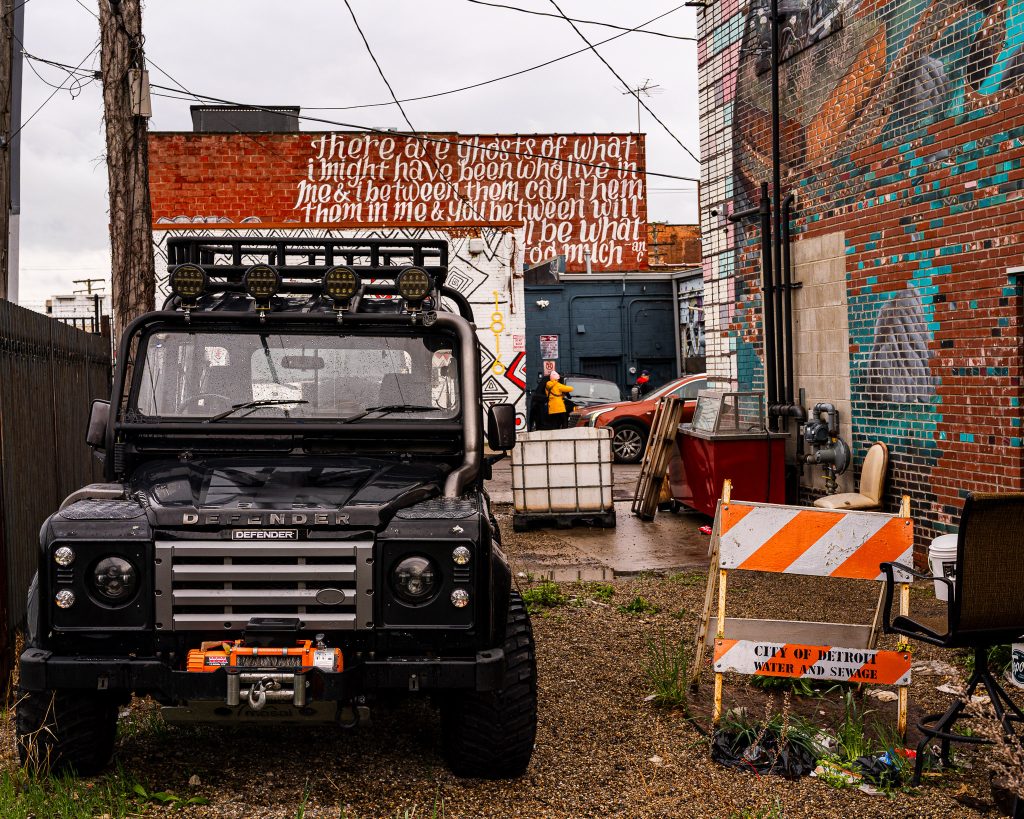 Large-scale mural in Eastern Market Detroit with layered graffiti textures and urban street art composition.