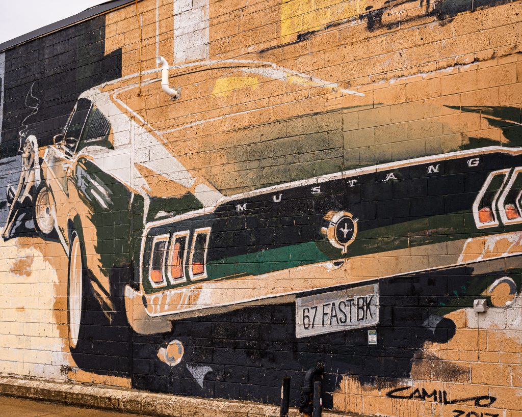 Large-scale mural in Eastern Market Detroit with layered graffiti textures and urban street art composition.