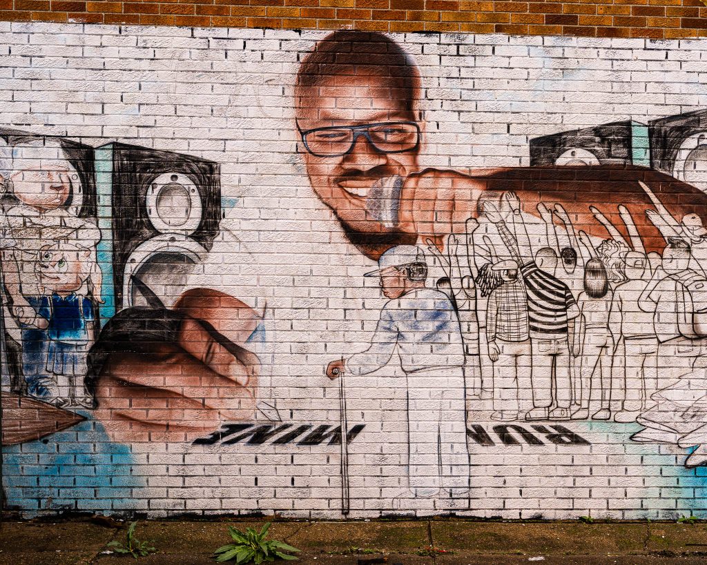 Large-scale mural in Eastern Market Detroit with layered graffiti textures and urban street art composition.