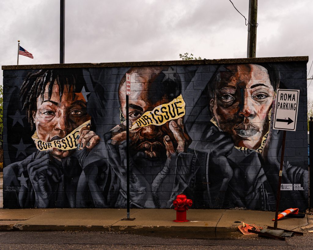 Large-scale mural in Eastern Market Detroit with layered graffiti textures and urban street art composition.
