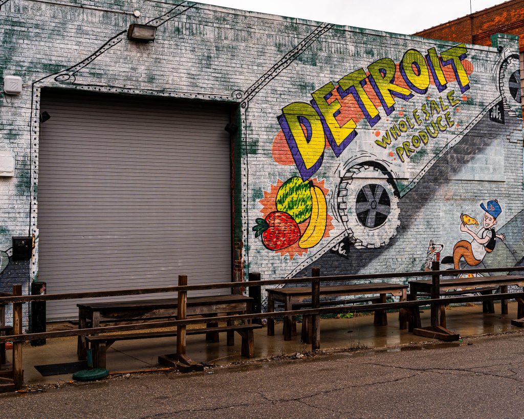 Large-scale mural in Eastern Market Detroit with layered graffiti textures and urban street art composition.