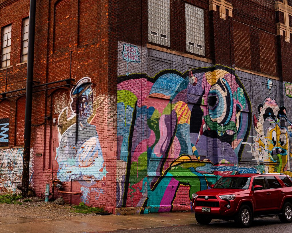 Large-scale mural in Eastern Market Detroit with layered graffiti textures and urban street art composition.