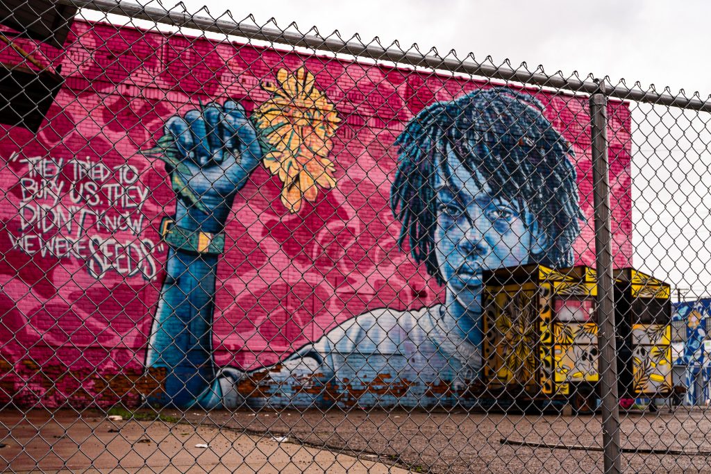 Large-scale mural in Eastern Market Detroit with layered graffiti textures and urban street art composition.