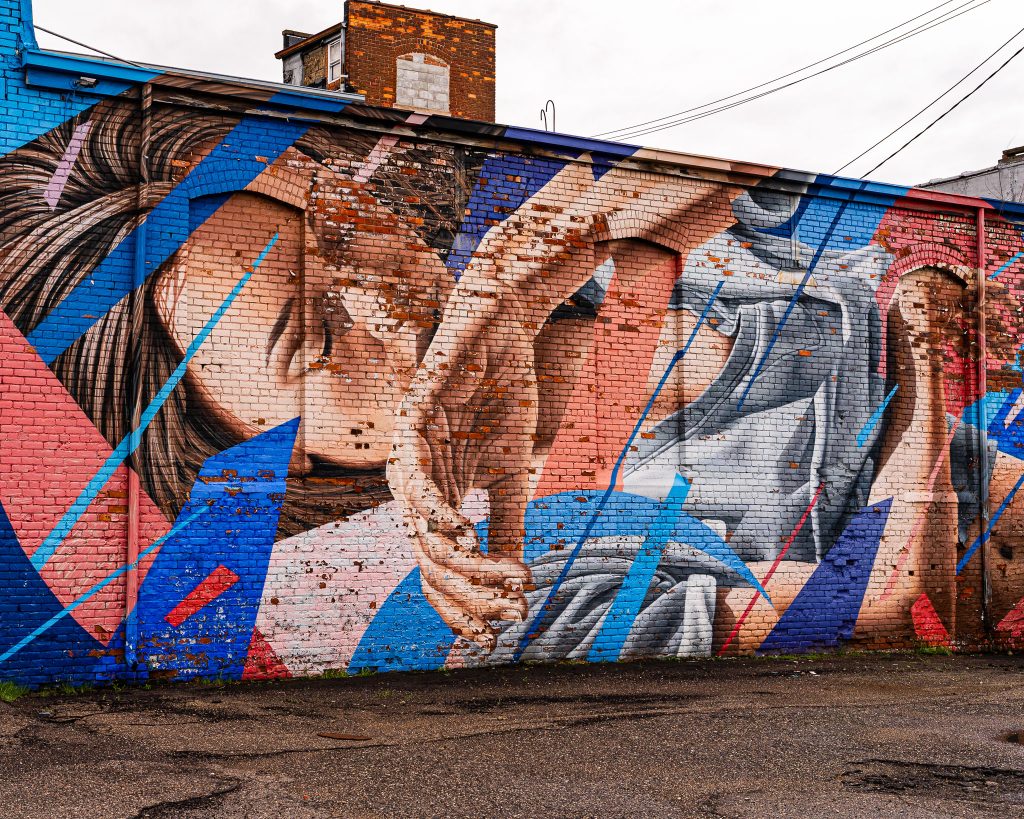Large-scale mural in Eastern Market Detroit with layered graffiti textures and urban street art composition.