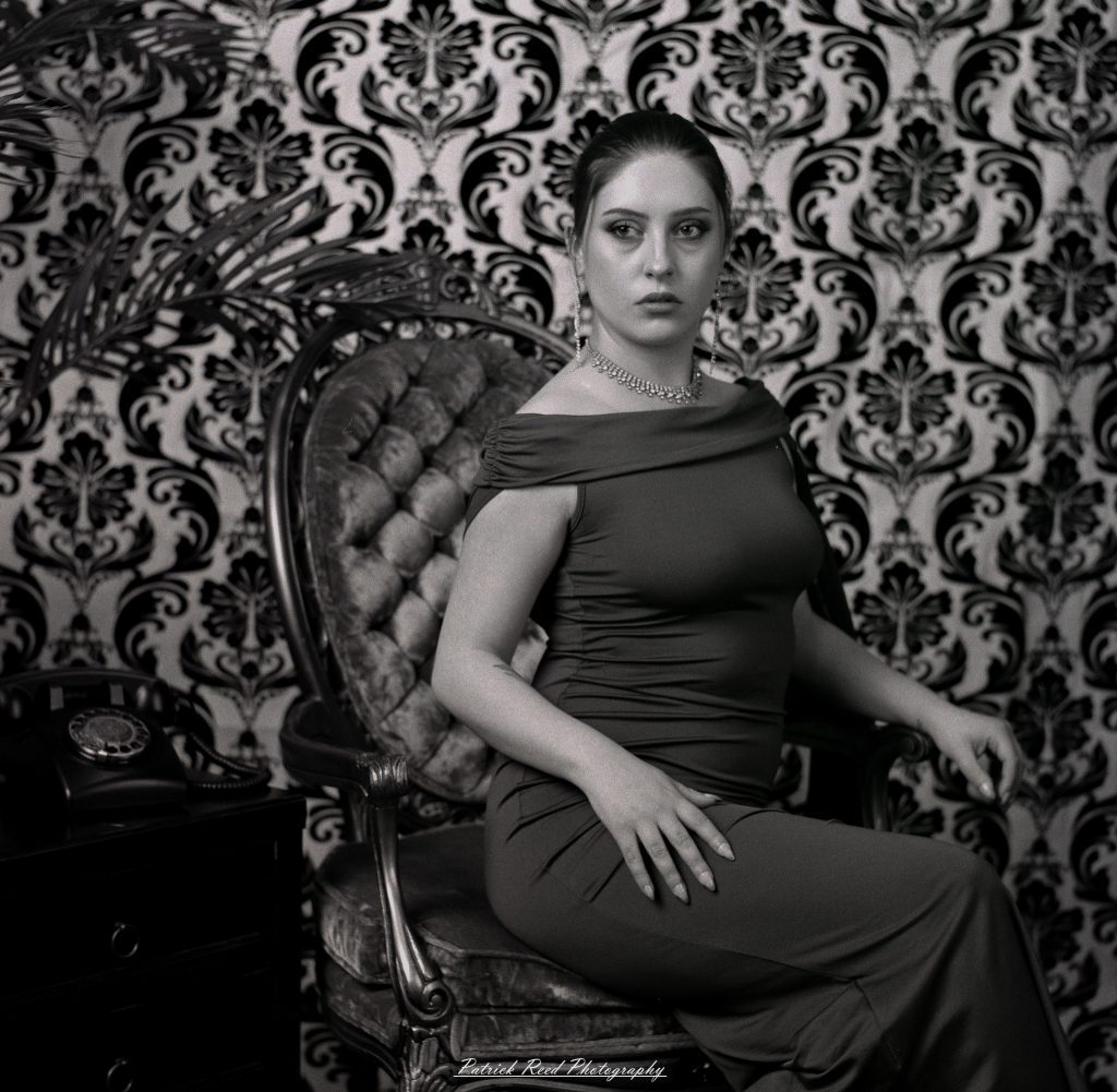 A vintage fashion portrait of Jinx, photographed on medium format film using a Mamiya C33. The session combines classic styling with the tonal depth and softness of analog photography, creating a timeless studio portrait inspired by mid-century fashion aesthetics.