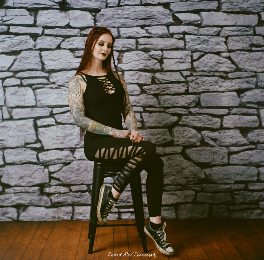A medium format film portrait of a model styled in a casual goth look, photographed using a Mamiya C33 camera with moody studio lighting and classic analog texture.