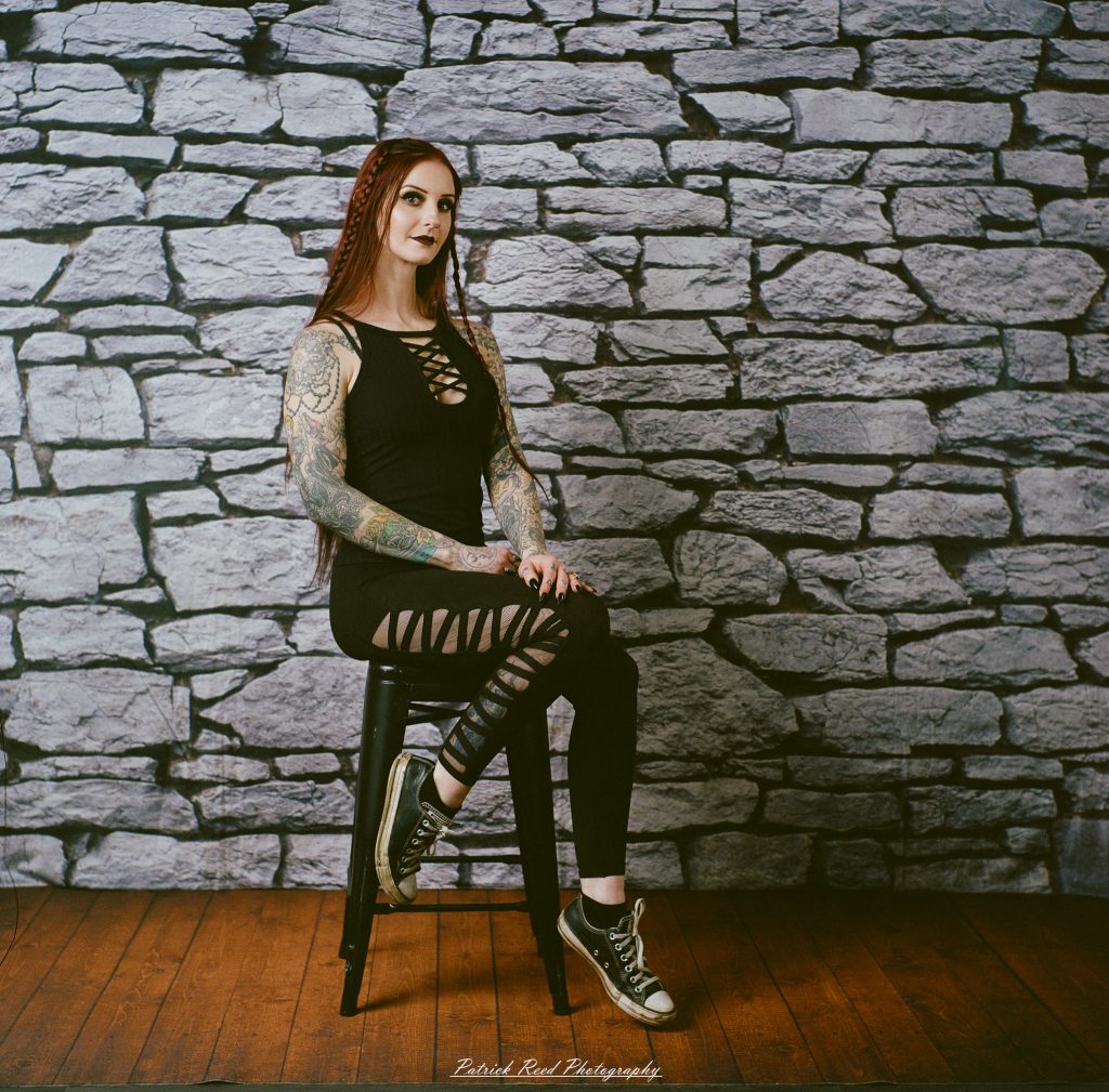 A medium format film portrait of a model styled in a casual goth look, photographed using a Mamiya C33 camera with moody studio lighting and classic analog texture.