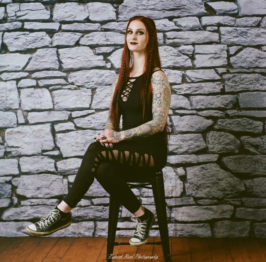 A medium format film portrait of a model styled in a casual goth look, photographed using a Mamiya C33 camera with moody studio lighting and classic analog texture.