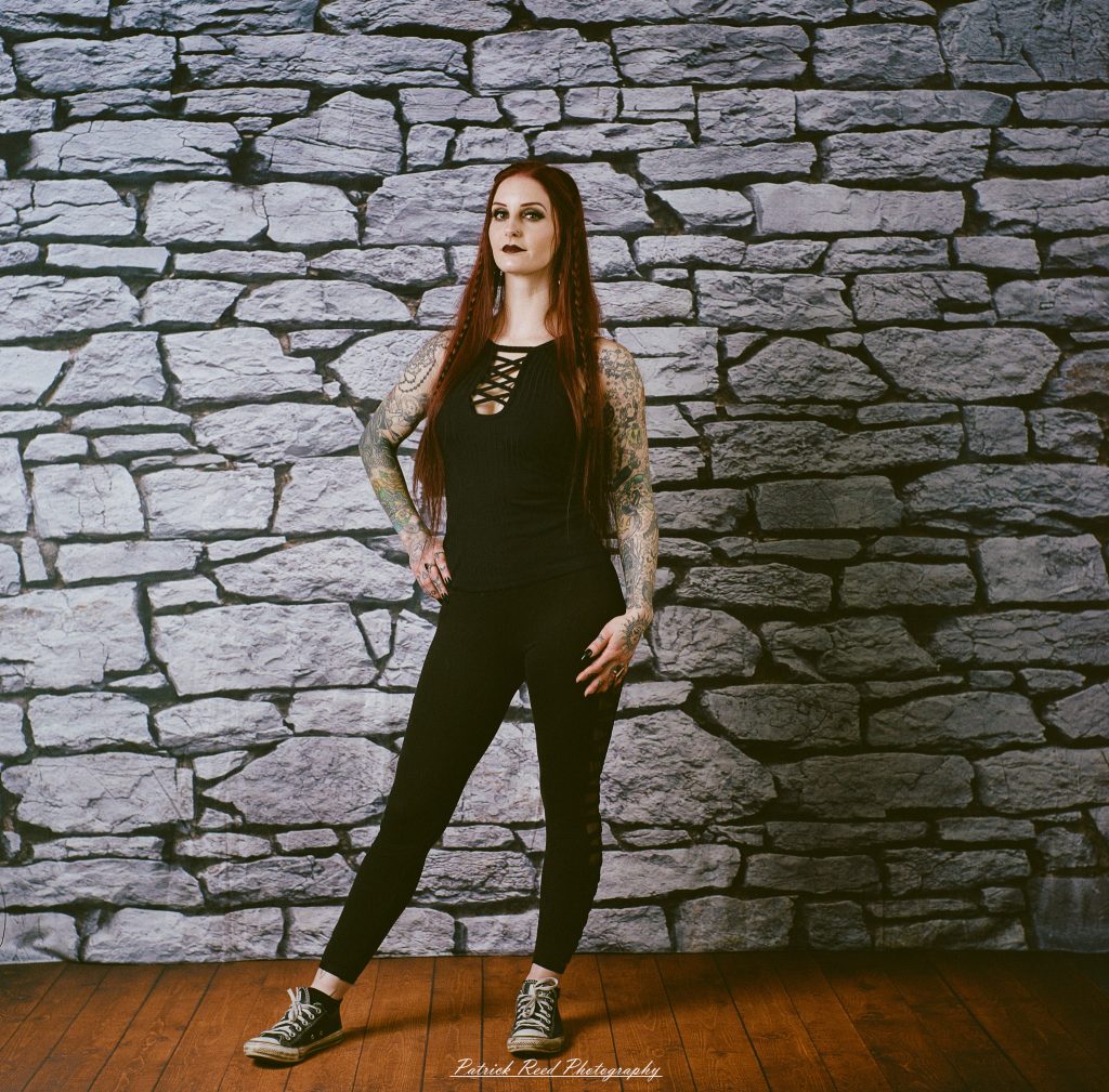 A medium format film portrait of a model styled in a casual goth look, photographed using a Mamiya C33 camera with moody studio lighting and classic analog texture.