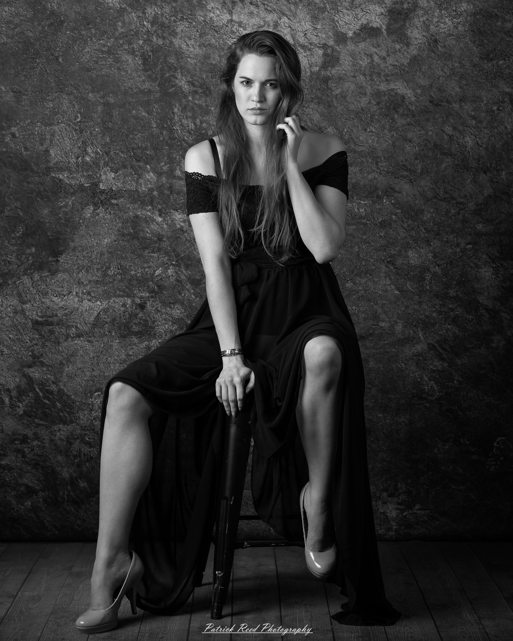 Black-and-white studio portrait of a woman seated with a contemplative pose and soft directional lighting.