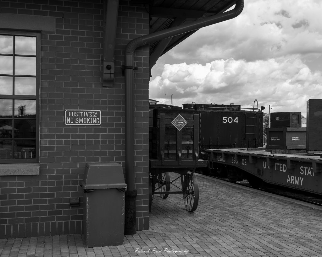 Black-and-white documentary photographs from the Steam Railroading Institute in Ohio, featuring historic steam locomotives, vintage passenger railcars, railroad machinery, restoration workshops, and industrial details preserving America's railroad heritage.