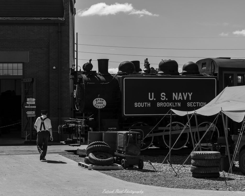 Black-and-white documentary photographs from the Steam Railroading Institute in Ohio, featuring historic steam locomotives, vintage passenger railcars, railroad machinery, restoration workshops, and industrial details preserving America's railroad heritage.
