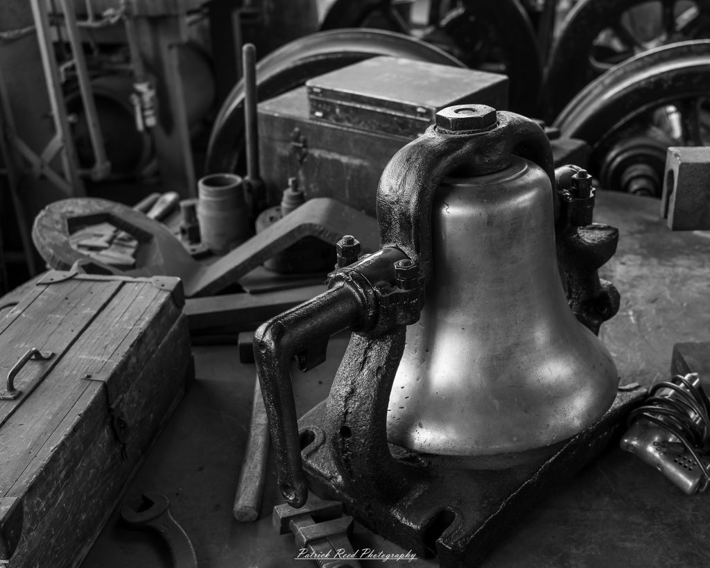 Black-and-white documentary photographs from the Steam Railroading Institute in Ohio, featuring historic steam locomotives, vintage passenger railcars, railroad machinery, restoration workshops, and industrial details preserving America's railroad heritage.