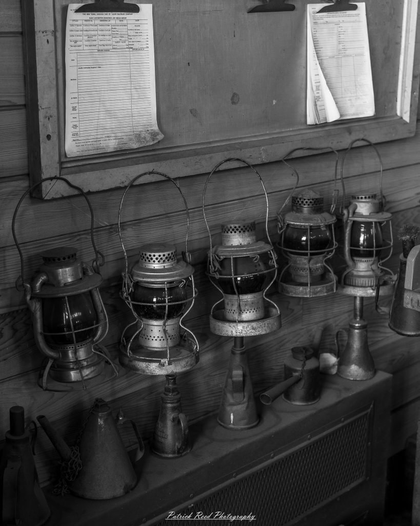 Black-and-white documentary photographs from the Steam Railroading Institute in Ohio, featuring historic steam locomotives, vintage passenger railcars, railroad machinery, restoration workshops, and industrial details preserving America's railroad heritage.