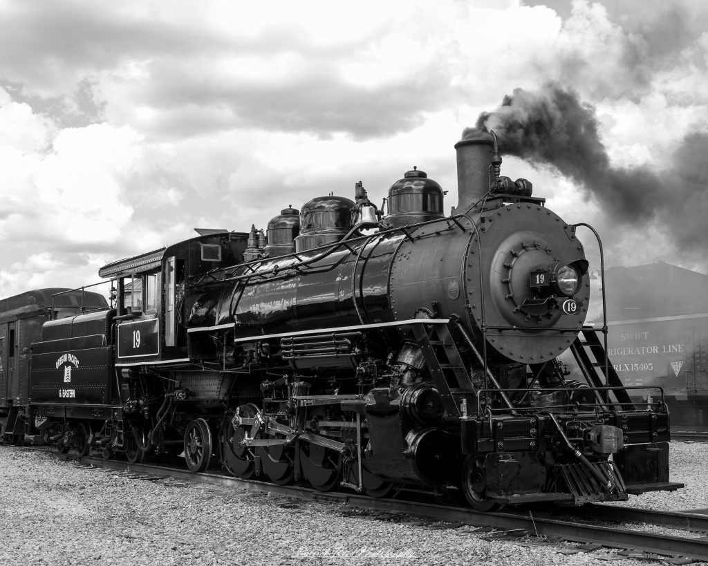 Black-and-white documentary photographs from the Steam Railroading Institute in Ohio, featuring historic steam locomotives, vintage passenger railcars, railroad machinery, restoration workshops, and industrial details preserving America's railroad heritage.