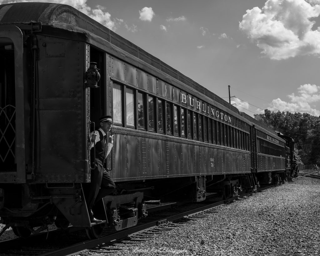 Black-and-white documentary photographs from the Steam Railroading Institute in Ohio, featuring historic steam locomotives, vintage passenger railcars, railroad machinery, restoration workshops, and industrial details preserving America's railroad heritage.