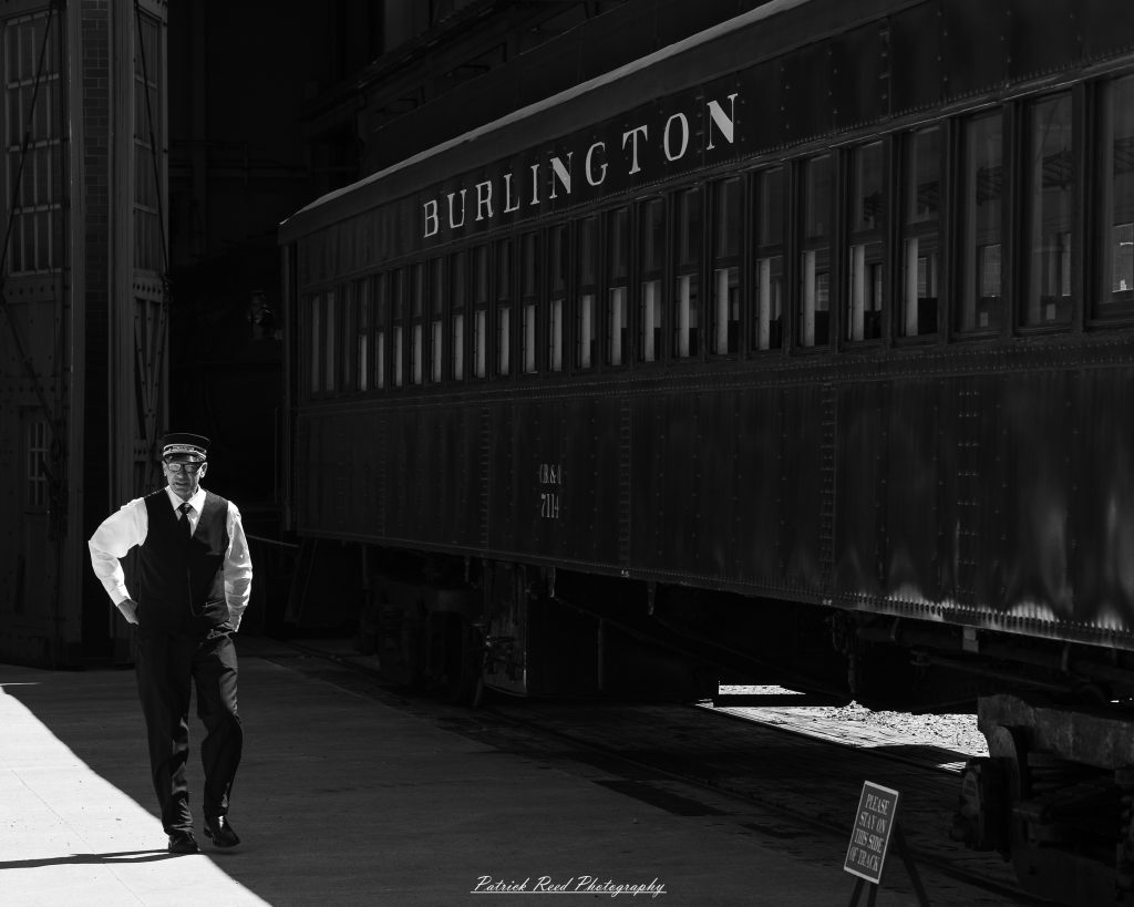 Black-and-white documentary photographs from the Steam Railroading Institute in Ohio, featuring historic steam locomotives, vintage passenger railcars, railroad machinery, restoration workshops, and industrial details preserving America's railroad heritage.
