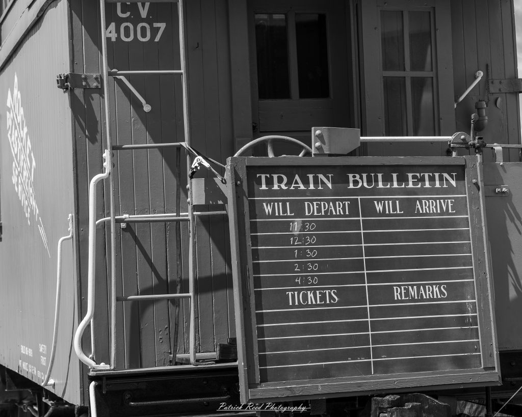 Black-and-white documentary photographs from the Steam Railroading Institute in Ohio, featuring historic steam locomotives, vintage passenger railcars, railroad machinery, restoration workshops, and industrial details preserving America's railroad heritage.