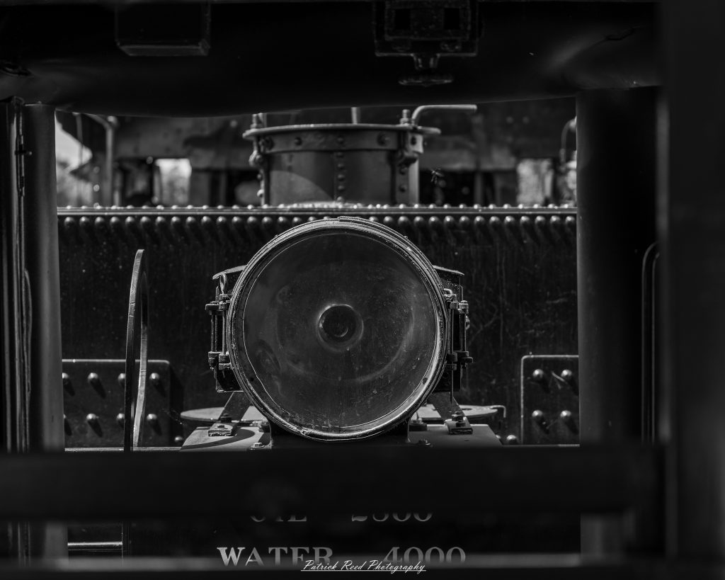 Black-and-white documentary photographs from the Steam Railroading Institute in Ohio, featuring historic steam locomotives, vintage passenger railcars, railroad machinery, restoration workshops, and industrial details preserving America's railroad heritage.