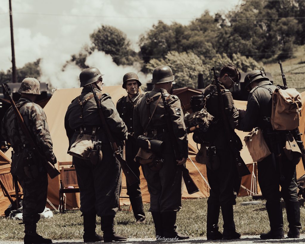 Documentary photographs of World War II reenactors at the Steam Railroading Institute, featuring authentic military uniforms, vintage trains, historical equipment, and living history demonstrations.