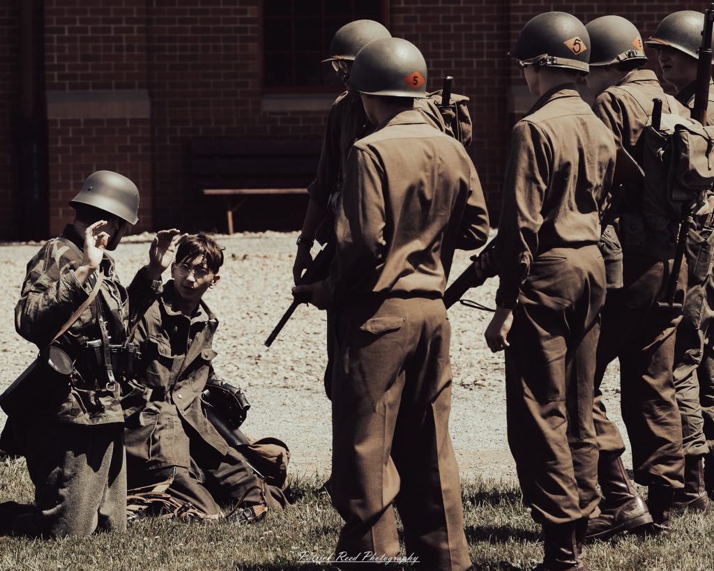 Documentary photographs of World War II reenactors at the Steam Railroading Institute, featuring authentic military uniforms, vintage trains, historical equipment, and living history demonstrations.