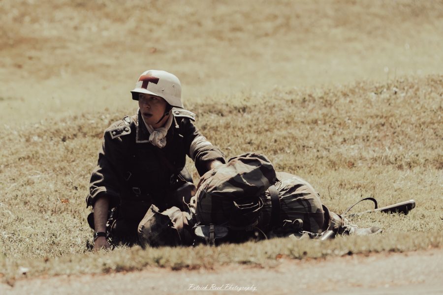 A group of World War II reenactors in period-accurate uniforms—American, German, and French Resistance—on a sandy shore during the D-Day Conneaut 2025 reenactment at Conneaut Township Park, Ohio.