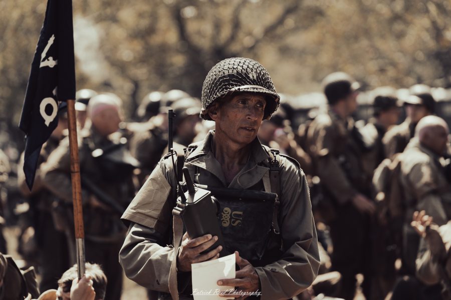 A group of World War II reenactors in period-accurate uniforms—American, German, and French Resistance—on a sandy shore during the D-Day Conneaut 2025 reenactment at Conneaut Township Park, Ohio.