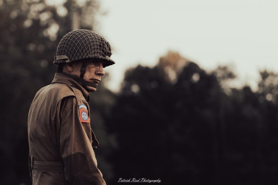 A group of World War II reenactors in period-accurate uniforms—American, German, and French Resistance—on a sandy shore during the D-Day Conneaut 2025 reenactment at Conneaut Township Park, Ohio.