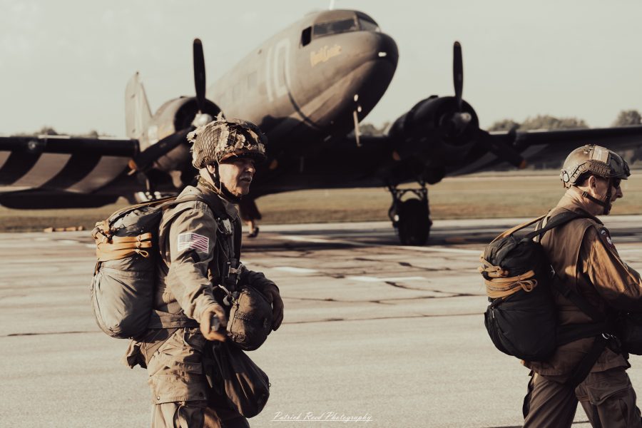 A group of World War II reenactors in period-accurate uniforms—American, German, and French Resistance—on a sandy shore during the D-Day Conneaut 2025 reenactment at Conneaut Township Park, Ohio.