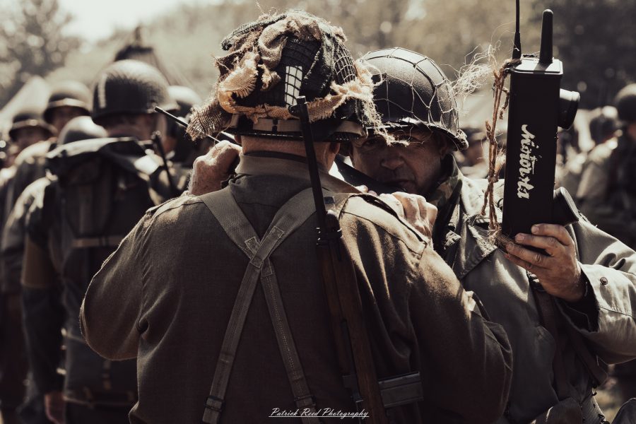 A group of World War II reenactors in period-accurate uniforms—American, German, and French Resistance—on a sandy shore during the D-Day Conneaut 2025 reenactment at Conneaut Township Park, Ohio.