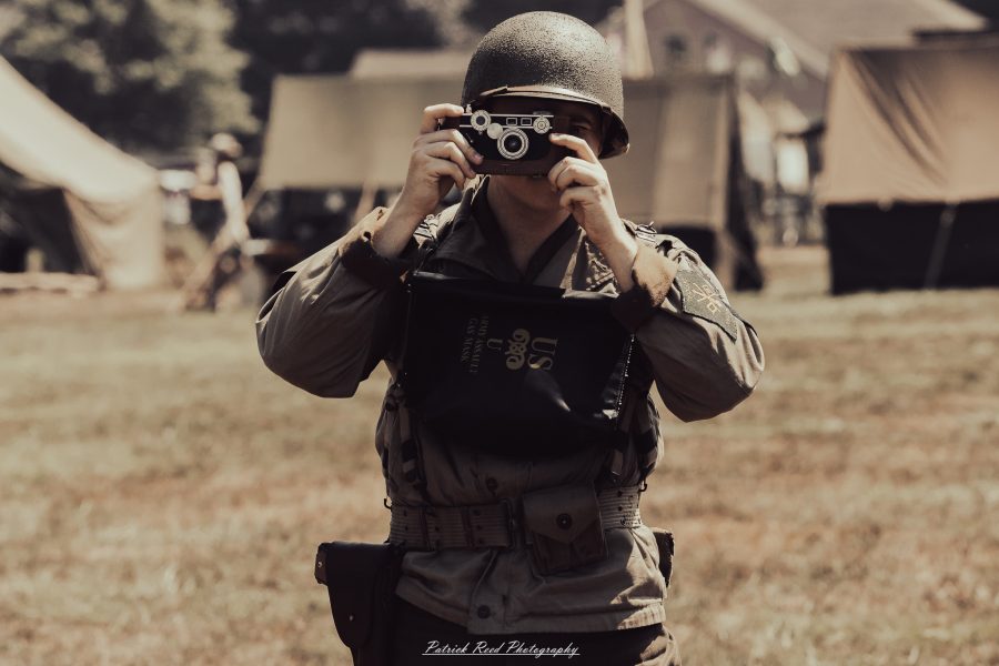 A group of World War II reenactors in period-accurate uniforms—American, German, and French Resistance—on a sandy shore during the D-Day Conneaut 2025 reenactment at Conneaut Township Park, Ohio.
