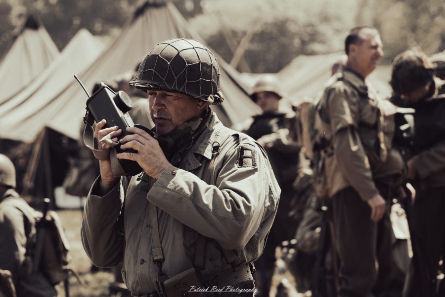 A group of World War II reenactors in period-accurate uniforms—American, German, and French Resistance—on a sandy shore during the D-Day Conneaut 2025 reenactment at Conneaut Township Park, Ohio.