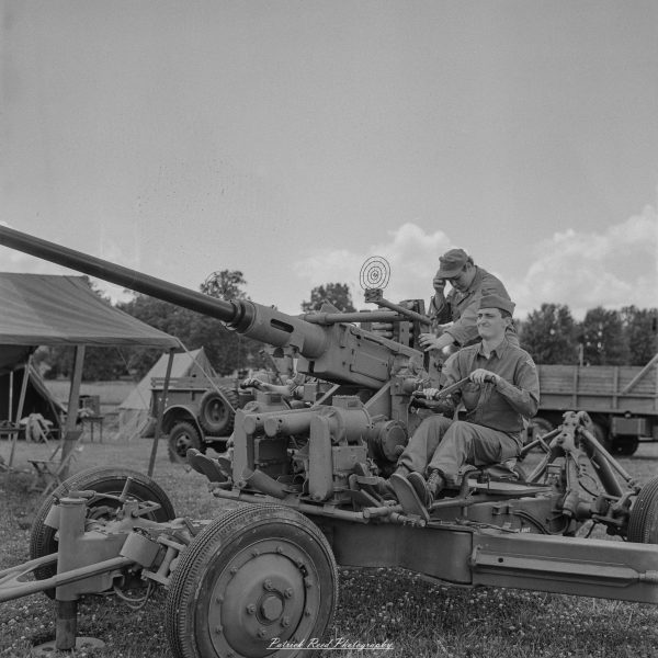 Vintage artillery cannon with reenactors posing beside the gun at an outdoor historical event