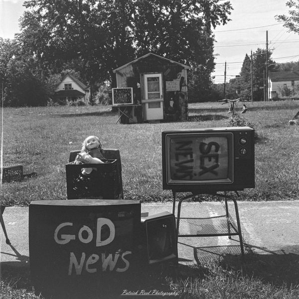 Discarded televisions painted with messages about news and politics in a black-and-white photograph of an outdoor art installation.