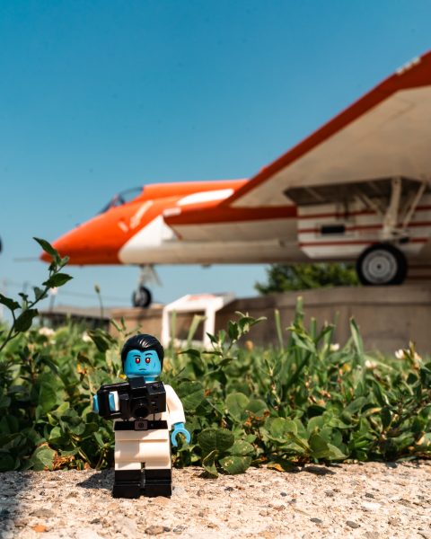 LEGO Grand Admiral Thrawn holding a camera in front of an orange-and-white aircraft.