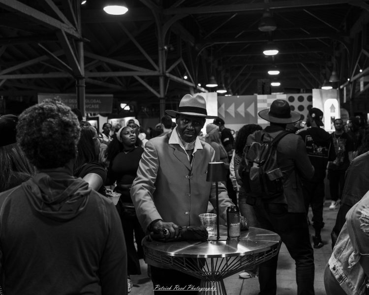 Crowd at a night market as a person raises an arm near the storefront entrance.